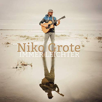 Albumcover von „Immer leichter“ von Niko Grote. In der Mitte steht ein Mann mit Gitarre an einem ruhigen Strand. Er trägt eine Mütze und Outdoor-Kleidung und blickt nach unten auf sein Instrument. Der sandige Boden ist teilweise von Wasser bedeckt, sodass sich der Mann und die Gitarre deutlich im Wasser spiegeln. Die Farben sind ruhig und natürlich, mit hellem Himmel und gedämpften Beigetönen. Der Schriftzug „Niko Grote – Immer leichter“ ist mittig über dem Bild platziert.
